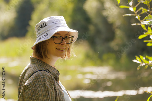 Canvastavla Smiling woman in a casual outfit enjoying a peaceful afternoon by the serene riv