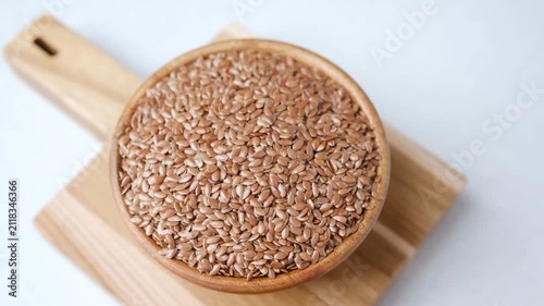 Bowl of flax seeds on a wooden board with a white background