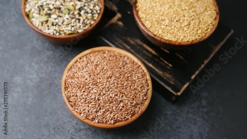 Three wooden bowls filled with various seeds on a dark background