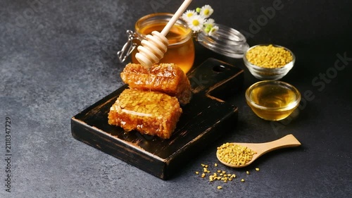 Honeycomb and bee pollen on a dark textured background with a honey dipper
