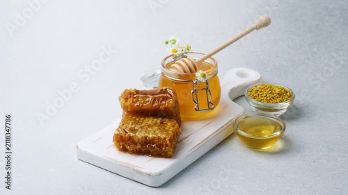 Honeycomb and honey served on a white board with small bowls of bee pollen and liquid honey