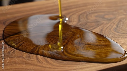 Olive oil pouring from bottle onto wooden cutting board