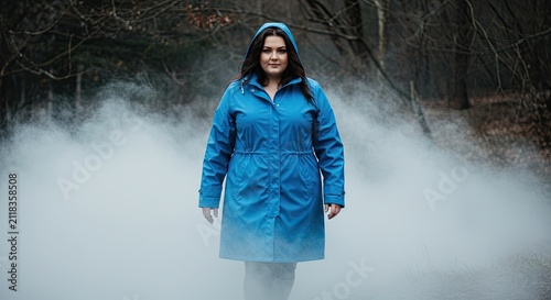 Woman in blue jacket standing in foggy forest environment