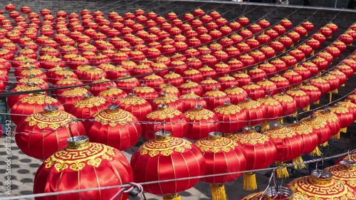 Rows of vibrant red Chinese lanterns hanging against an ancient brick wall background.