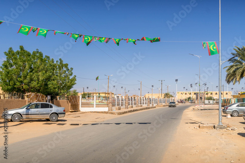 Atar market city street in Mauritania, with Mauritaniann flags, a small town in West Africa Sahel region, with dusty road during the hot summer day.
