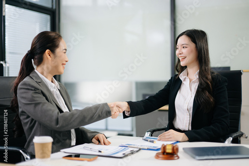 Asian lawyer and client shaking hands after signing a business contract in a modern office, symbolizing trust, legal agreement, partnership