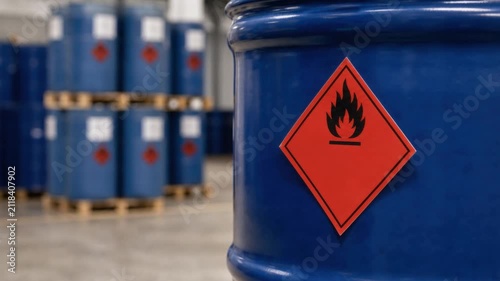 Blue industrial barrels with flammable hazard signs in warehouse storage for chemical safety and fire prevention