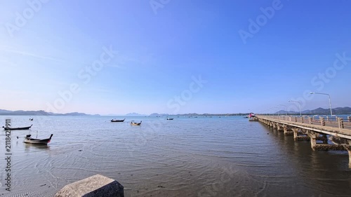 Concrete pier extending into calm tropical water beside small boats