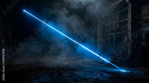 Blue laser beam in dark smoke-filled industrial space.