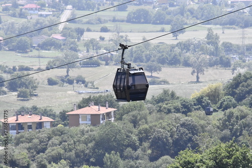 Cable car cabin moving above rural valley and village on a sunny day