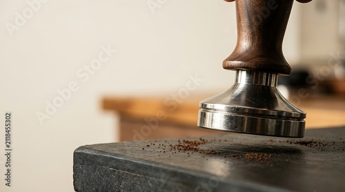 Professional coffee tamper pressing grounds on a dark counter