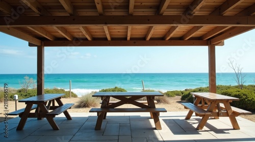 Wooden picnic tables under a pavilion overlooking the tropical ocean beach.