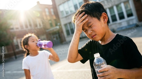 Two children feeling exhausted and thirsty on a hot sunny day.