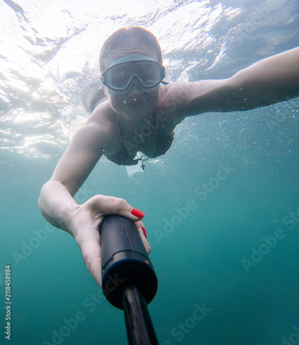 Obraz na plátne Snorkeling selfie captures young woman swimming underwater with goggles in turqu
