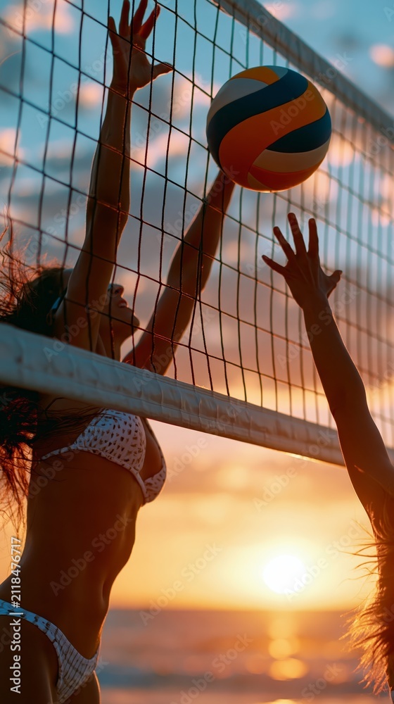 Fototapeta premium Women playing beach volleyball at sunset reaching for the ball over the net with warm golden hour lighting.