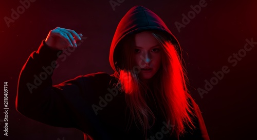 Young Woman Wearing Black Hoodie with Red Lighting Effect in Dark Studio