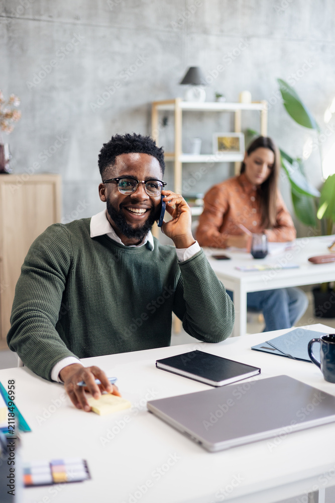 Fototapeta premium Black entrepreneur smiling talking on phone in office