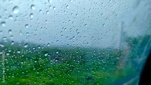 rain drops on a glass of the window of the car in the rainy season.