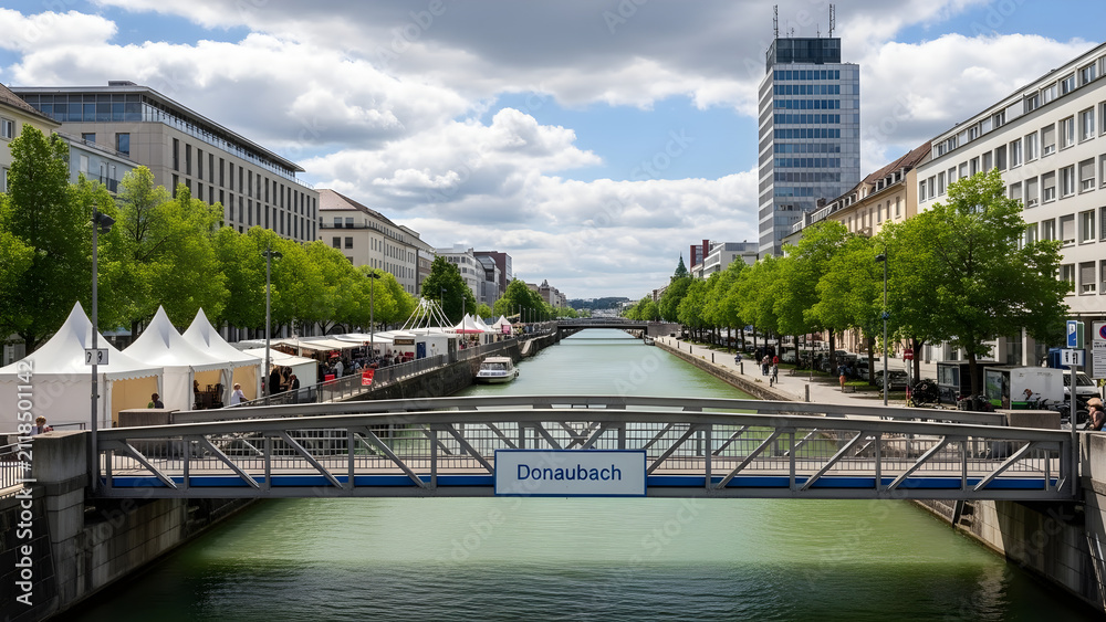 Fototapeta premium Scenic view of a tranquil urban canal with a pedestrian bridge and vibrant tree-lined streets during a sunny summer day in a bustling city