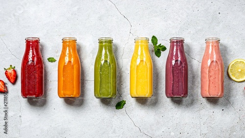 Colorful fresh fruit and vegetable juice bottles arranged on concrete background