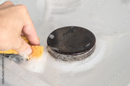 Принти на полотні Photo of manual cleaning of the surface of a gas stove from small dirt with a cl