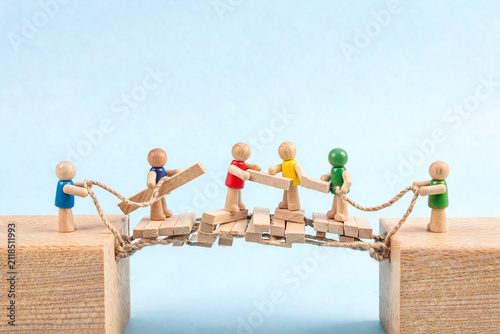 Wooden Figures Building a Bridge Together