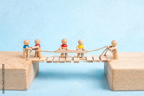 Wooden Figures Building a Bridge Together