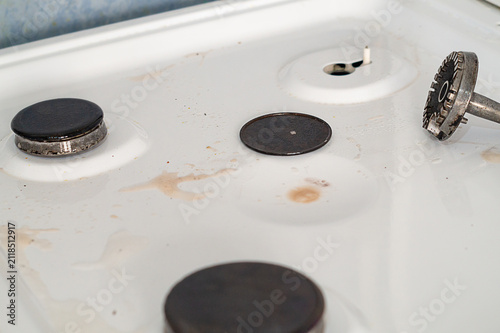 фотографія Dismantled gas stove surface with sprayed cleaning agent to pre-dissolve dirt