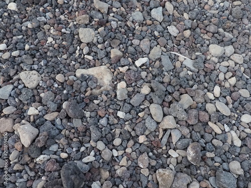 Top down close up view of colorful small volcanic pebbles and stones on beach.