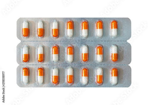 Fotografie Blister pack with orange and white capsules on gray background.