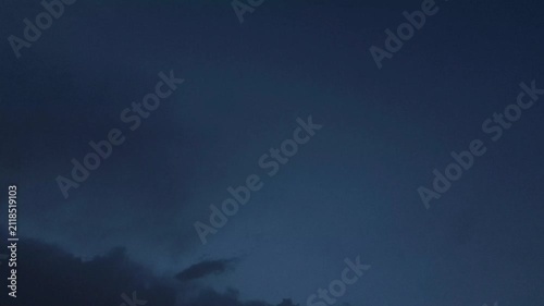 Curious clouds moving in the navy blue sky at dusk
