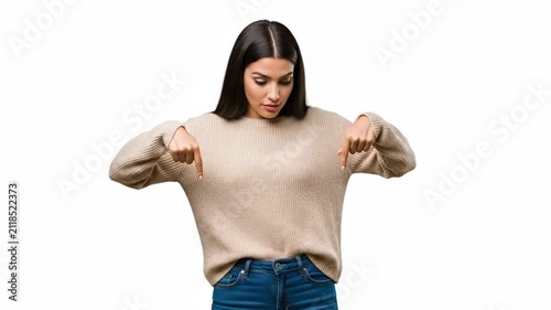 A young woman wearing a beige sweater pointing down with both her hands