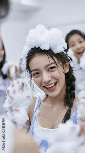 Joyful Bubble Bath Fun: A young Asian woman with a bright smile and braided hair is surrounded by bubbly foam, enjoying a playful and refreshing bath with friends in the background.