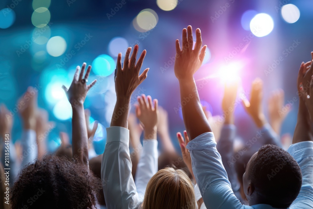 Fototapeta premium Crowd celebrating with raised hands during vibrant event at nighttime venue