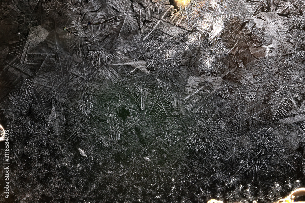 Obraz premium Ice crystals freezing on a black background, abstract winter photo surface