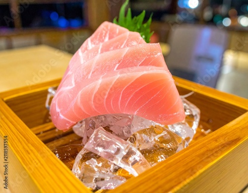 Fresh tuna sashimi slices served on ice in a wooden box, showcasing gourmet Japanese seafood dining