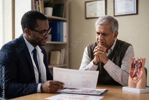 Doctor, physician or medical specialist explaining concerning examination, laboratory test, diagnosis or treatment results to patient, couple or family during serious healthcare consultation