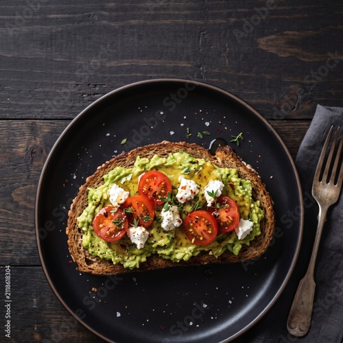Fresh avocado toast with cherry tomatoes and feta on dark plate