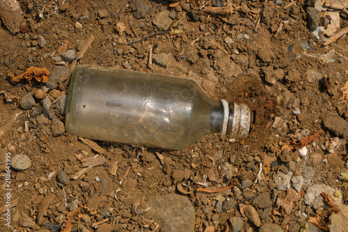 Foto Top view of a dirty discarded glass bottle on dry soil