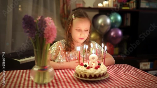 Little girl blowing out birthday candles and making a wish during her eighth birthday celebration at home