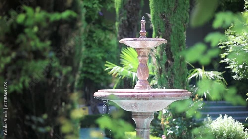 Fountain with flowing water in the garden of the Grand Mosque of Paris, surrounded by lush greenery and soft natural light
