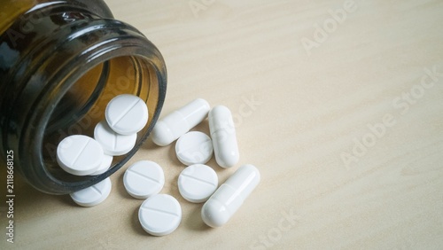 фотографія Assorted pills spilled from bottle on light background.