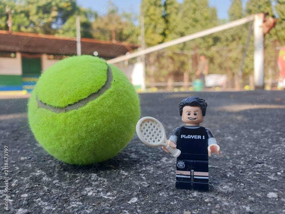 Fototapeta premium Indonesia - August 31, 2024 : Mini toy of action figure at tenniscourt with blurred background. Sport photography concept design. Miniature Young man athlete at tennis club.