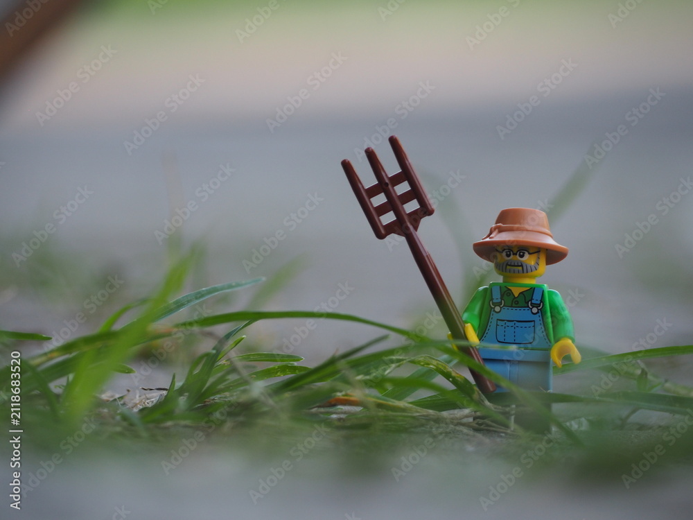 Fototapeta premium Indonesia - January 6, 2019 : Mini toy of action figure with blurred background. Toy photography concept. Farmer with harrow at green grass land conceptual design.
