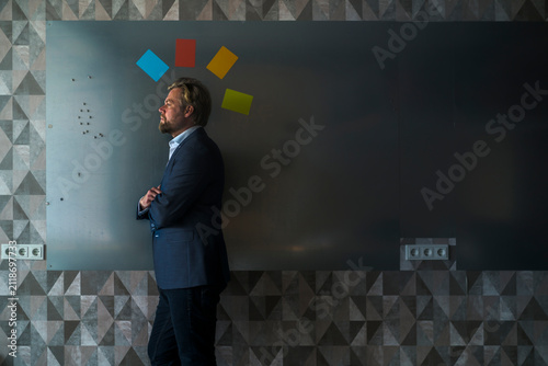 Businessman standing in front of magnet wall with mohican from colorful sticky notes