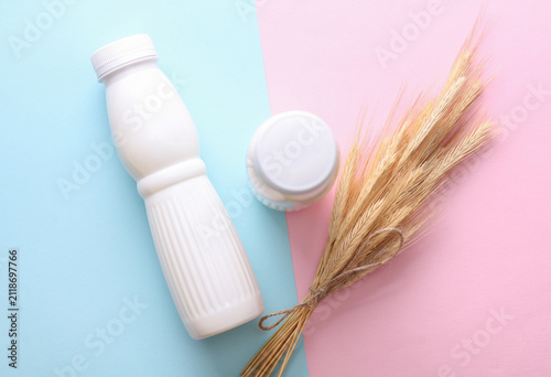 White plastic bottles of cereal yogurt and wheat ears on pink blue background. Healthy eating concept.
