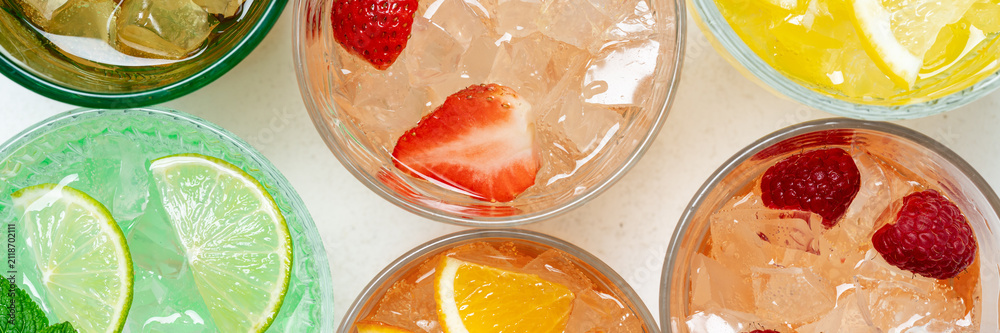 Fototapeta premium Colorful fruit drinks banner close up with ice and citrus