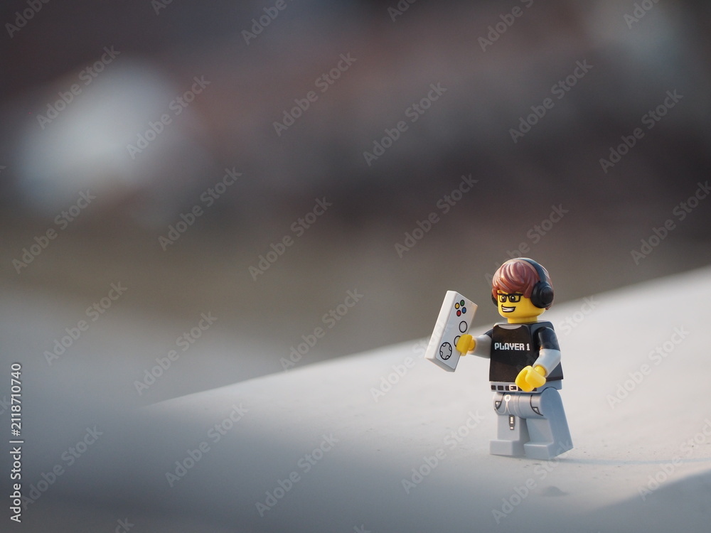 Fototapeta premium Indonesia - August 17, 2019 : Mini toy of action figure at outdoor with blurred background. Toy photography concept design. Young man character enjoying music with headphones and smartphone.