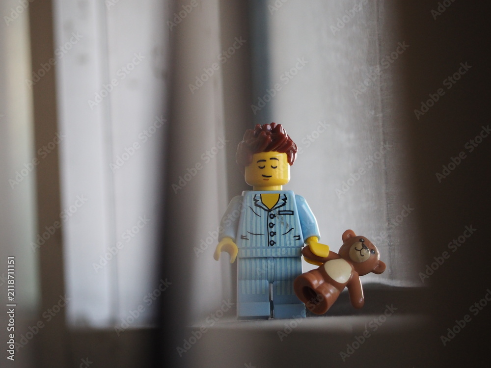 Fototapeta premium Indonesia - September 12, 2025 : Mini toy of action figure at table with blurred background. Miniature photography concept design. Minifigure of people character wearing pajama with teddy bear at home