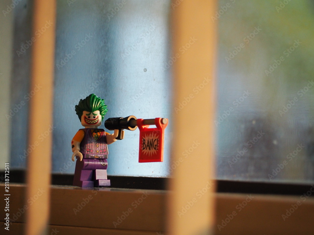 Fototapeta premium Indonesia - September 12, 2025 : Mini toy of action figure at table with blurred background. Miniature photography concept design. Minifigure of Joker clown character with bicycle at sunset time.